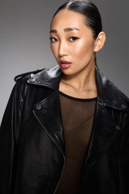 Moda, Asyalı kadın, siyah deri ceket, poz, kalçalar. Asyalı bir kadın kameraya şık siyah deri ceketli bir poz veriyor. Kendine güveni ve tavırları var..