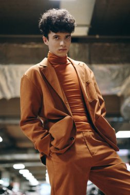 A fashionable male model wearing a brown suit and turtleneck, exuding confidence against a blurred urban background clipart