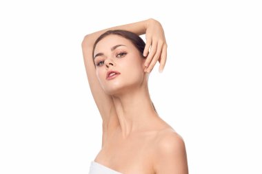 Havlulu çekici bir kadın, beyaz bir arka plana karşı elleri başının üstünde poz veriyor. Kaplıca ya da güzellik konseptinde bir kadın modelin portresi. izole resim.