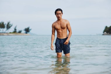 Neşeli Asyalı Adam Tropikal Cennet 'te Aktif Su Sporlarının keyfini çıkarıyor, Gülümsüyor ve Mavi Okyanusta Eğleniyor