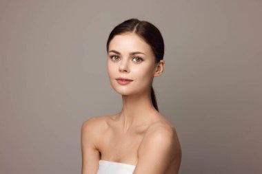 Gri arka planda poz veren zarif beyaz elbiseli çekici bir kadın. Güzel, genç bir mankenle fotoğraf çekimi. profesyonel fotoğrafçılık konsepti.