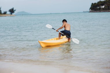 Mutlu Asyalı Adam Tropikal Sahilde Kayak yapıyor, Yaz Tatilinin tadını çıkarıyor