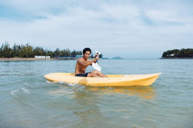 Eğlence dolu Kano Macerası: Mutlu bir Asyalı Adam Tropikal Sahili Kanoyla Keşfeder