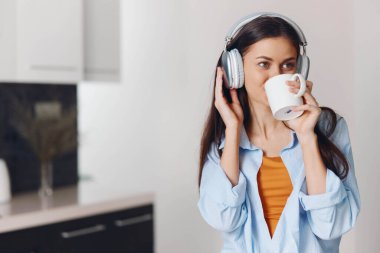 Mutfak ortamında müzik ve kahveyle sakin bir anın tadını çıkaran bir kadın.