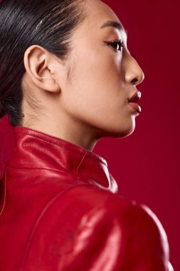 Kırmızı deri ceketli, at kuyruklu, gözleri kapalı Asyalı bir kadın. şık esmer model..