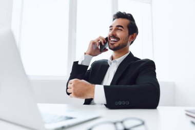 Ofis işadamı masasında oturuyor ve dizüstü bilgisayarda çalışıyor ve telefonla konuşuyor, modern takım elbise, finans ve başlangıç konsepti ve veri analizi, parlak bir ofiste çalışma tarzı. Yüksek kalite fotoğraf