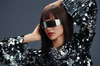 Woman, sequinned top, sunglasses a stylish woman in a sequinned top and sunglasses, hand on head, head tilted, gazing confidently at the camera clipart