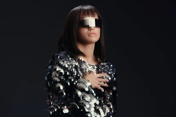 stock image A woman in a sequinned dress with a blindfold over her face, her hands on her chest, stares directly at the camera, evoking a sense of mystery and elegance