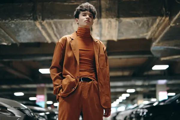 stock image A fashionable male model wears an orange suit and turtleneck, posed among parked cars in an urban setting