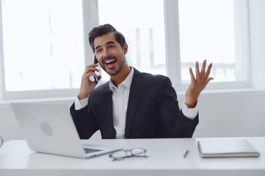 Kapalı alandaki mutlu iletişim konuşmaları başarılı ofis erkek laptop iş adamı Kafkasyalı gülüşlü telefon işi çekici bilgisayar teknolojisi.