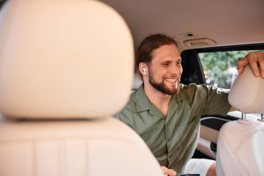 Uzun saçlı ve kulaklıklı neşeli bir adam bir arabada rahatça oturur, çevresiyle meşgul olur, modern yaşam tarzını gözler önüne serer.