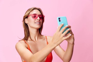 Hayat dolu yaz titreşimleri şık mayo giymiş genç bir kadın parlak pembe arka planda selfie çekiyor.
