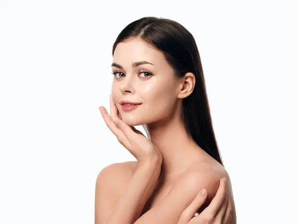 stock image Attractive young woman with hands on her face posing on a white background. a beautiful portrait of a woman with a delicate expression. ideal for beauty and fashion concepts.