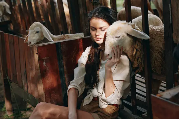 stock image A woman is sitting in front of a fence with sheep in front of the fence