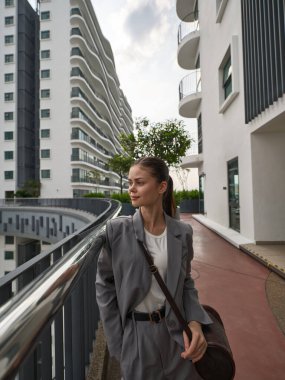 The image captures a confident woman in formal attire, set against a backdrop of sleek buildings and vibrant nature clipart