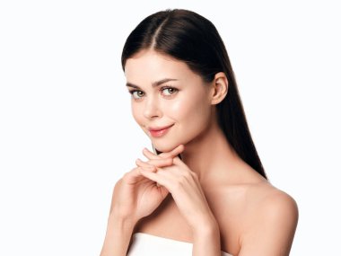 Elleri çenesinde poz veren ve doğrudan kameraya bakan genç ve güzel bir kadın. beyaz arkaplanda izole.