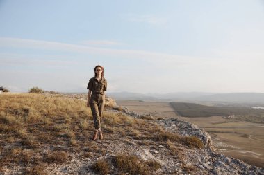 Macera yolculuğu sırasında tepedeki vadi ve dağların panoramik manzarasını seven bir kadın.