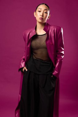 Moda, Asyalı, güzellik, kadın, mor deri ceket, siyah pantolon, poz, arka plan. Asyalı bir kadın aynı mor arka plana sahip şık bir mor deri ceket ve siyah pantolon içinde poz veriyor. O...