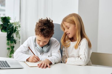 Kafkasyalı mutlu erkek ve kız evde oturma odasında oturmuş laptoplar ve kulaklıklarla ders çalışıyorlar. Elde ettikleri kazanç aktivitelerine dalmış durumdalar. Kardeşler teknoloji ile odaklanmış ve birbirlerine bağlılar.