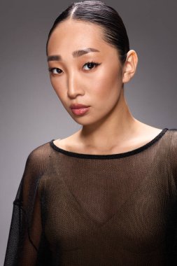 Asyalı kadın, moda, katıksız bluz, poz, kamera, yan bakış. Tarz sahibi Asyalı bir kadın dikey bir bluz giyiyor ve kameraya güvenli bir şekilde poz veriyor..