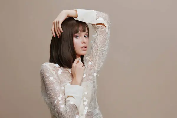 stock image Portrait of a beautiful young woman with short brown hair posing in front of a beige background, showcasing her elegant style and natural beauty