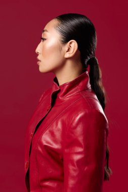 Kırmızı deri ceketli, at kuyruklu, yana bakan Asyalı bir kadın. moda ve stil sahibi Asyalı güzellik konsepti.