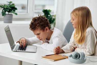 Mutlu Kafkas kardeşler oturma odalarında oturmuş dizüstü bilgisayar ve tablet kullanarak para kazanıyorlar. Erkek ve kız derinden konsantre olmuş, kulaklık takıyor, daktilo ediyor ve ders çalışıyorlar.