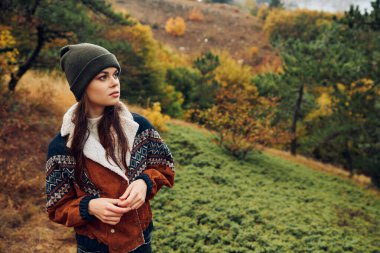 Sakin ormanda sonbaharın güzelliğinin tadını çıkaran şık genç bir kadın.