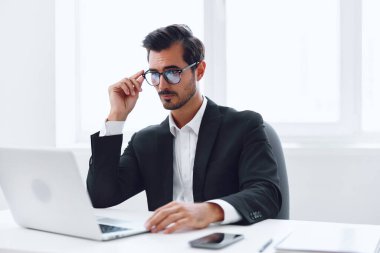 Adam ofis masası gözlükleri gündelik dizüstü bilgisayarda çalışırken kafaları karışmış. Yorgun beyaz, kapalı alanda oturuyor.