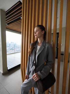 Görüntü, şehir manzaralı şık, modern mimarinin yanında profesyonel bir kadını gösteriyor.