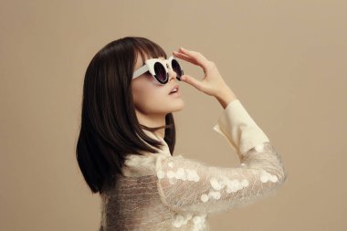 Kadın, beyaz gömlek, güneş gözlüğü beyaz gömlekli ve güneş gözlüklü bir kadın elleri başının üstünde, gözleri kapalı düşünceye dalmış ya da muhtemelen görünmeyen bir şeye tepki veriyor.