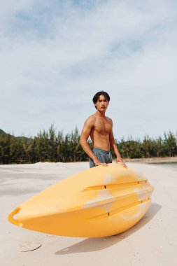 Keyifli Kano Macerası: Mutlu Asyalı Adam Tropikal Plajda Kürek ve Kanoyla Yaz Tatilinin Tadını Çıkartıyor