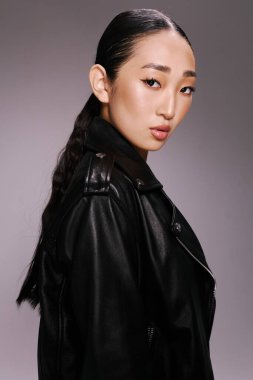 Asyalı güzellik, moda, kadın, siyah deri ceket, kameraya poz verme, eller kalçada. Şık Asyalı bir kadın kameraya poz verirken parlak siyah bir deri cekete güvenir..