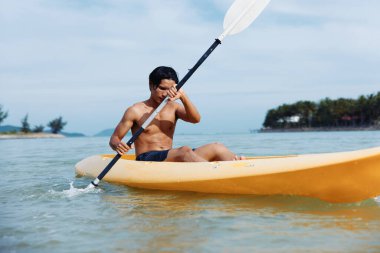 Serene Yaz Kayak Macerası: Mutlu Asyalı Adam Tropikal Sahilde Kayak Yapıyor