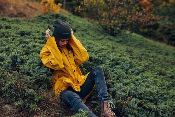 Sarı yağmurluklu Serene Woman Bir Tarlanın ortasında oturan Doğanın tadını çıkaran Güzellik