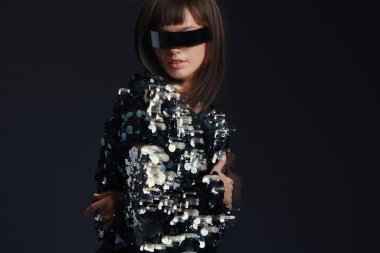 A woman wearing stylish sunglasses and a shimmering sequinned jacket poses confidently against a dark background, exuding elegance and sophistication clipart