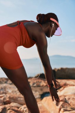 Fitness meraklısı okyanus arka planıyla antrenman yapmaya hazırlanıyor. Kararlılık ve sağlıklı yaşam tarzı sergiliyor.