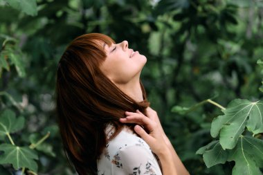 Bakışları gökyüzüne yemyeşil yaprakların arasında dingin bir düşünceye dalmış.