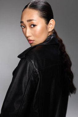 Asyalı kadın siyah deri ceketli at kuyruklu poz veren kamera. Şık ve şık görünüm..