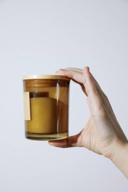 Beyaz arka planda mum olan cam bardakla el ele tutuşmak. Titreyen alevlerin yarattığı sıcak ve sıcak atmosfer. Rahatlamak ve romantik bir ortam yaratmak için mükemmel. ürün için ideal