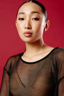 Saf bluzlu Asyalı bir kadın canlı kırmızı bir arka plana karşı poz veriyor..