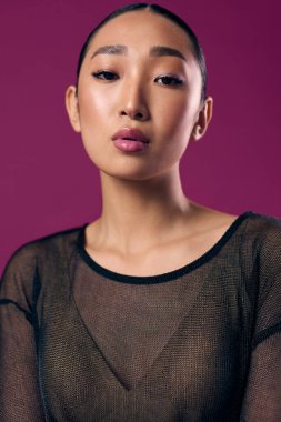 Mor arka planda poz veren saf giysili moda Asyalı kadın gözleri kapalı ve dudaklarında pembe ruj izi var..