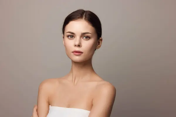 stock image Beautiful young woman with arms crossed posing on a gray background, close-up of her beautiful face.