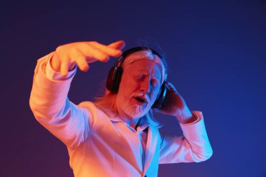 Müziğe dalmış yaşlı bir adam, kulaklık takıyor ve şık beyaz bir ceket giyiyor. Renkli arka plan maviden turuncuya kayıyor, enerjik ve neşeli bir atmosfer yaratıyor.