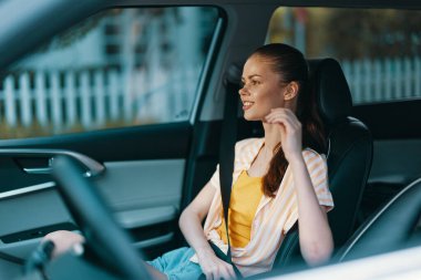 Emniyet kemerini takmış, gülümseyen neşeli genç bir kadın, özgürlük ve güvenlik hissi veriyor. İç mekan şık ve çağdaş, araba tutkunları için mükemmel.