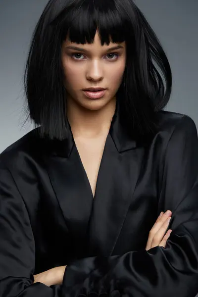 stock image Woman, black hair, black suit, posing a professionally dressed woman with black hair stands confidently, arms crossed, and hands on her hips, exuding strength and authority in a business environment