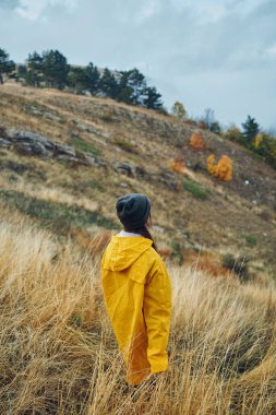Yalnızlık ve sükunet Parlak sarı yağmurluklu yalnız bir figür Uçsuz bucaksız bir tarlanın ortasında tepede duruyor