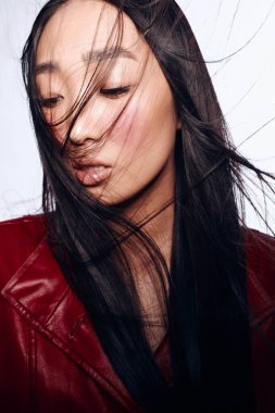 Kırmızı deri ceketli, dalgalı siyah saçlı güzel bir kadın. Rüzgâra karşı zarif ve kendinden emin.