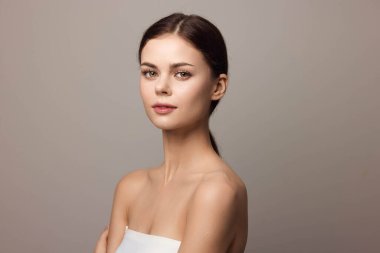 Gri bir arka planda kollarını kavuşturmuş güzel bir genç kadın..