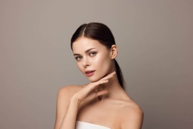 Elleri çenesinde kameraya bakan genç ve güzel bir kadın. Modaya uygun ve şık, bu görüntü kendine güven ve cazibe yayıyor. Kişisel markalaşma ya da yaşam tarzı içeriği için mükemmel.